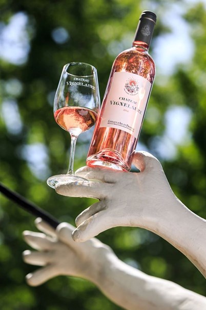 A garden sculpture at the estate holding a glass of Vignelaure rosé